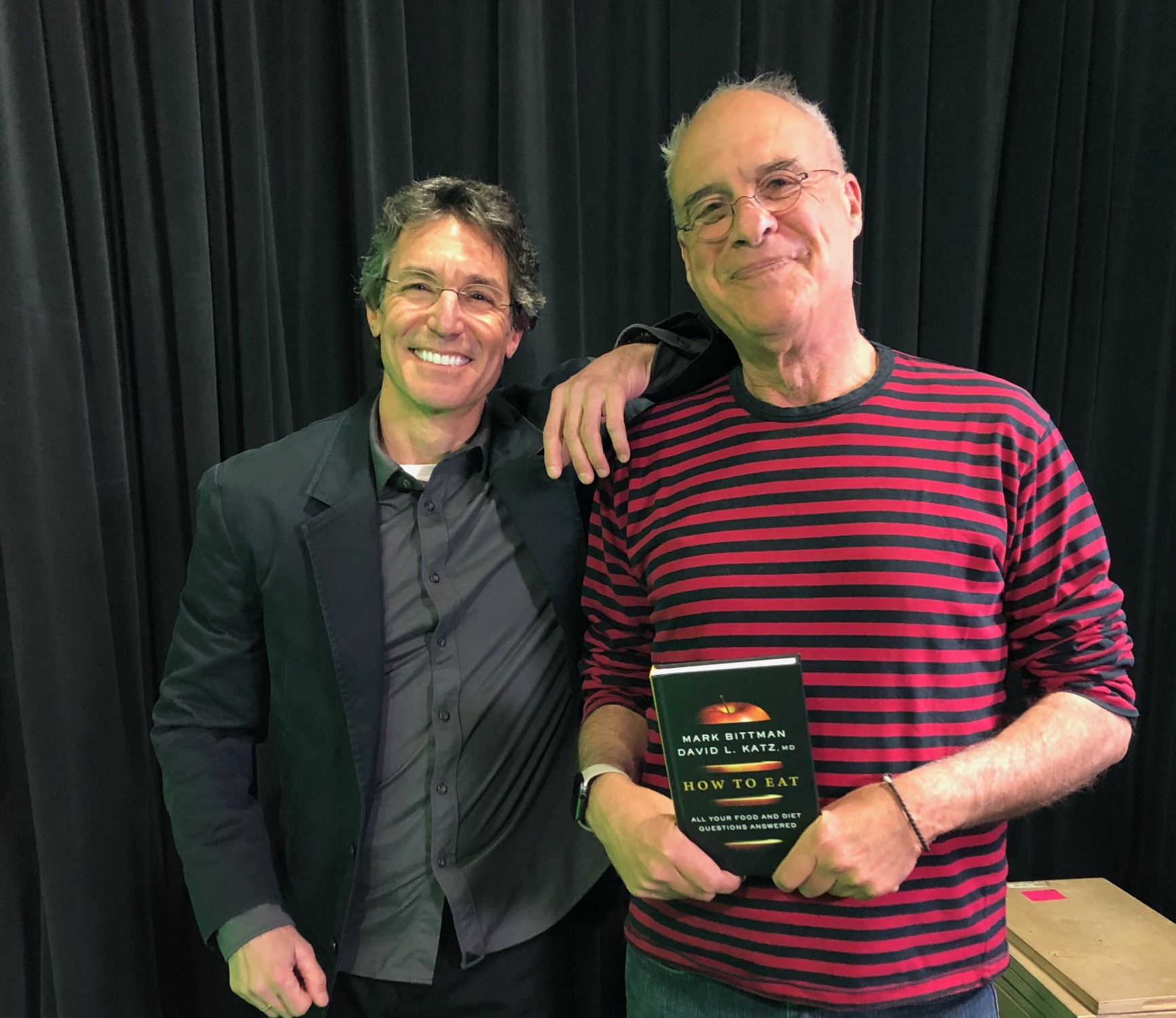 David L Katz MD on left and Mark Bittman on righ, holding a copy oof their new book, "How to Eat: All Your Food and Diet Questions Answered."
