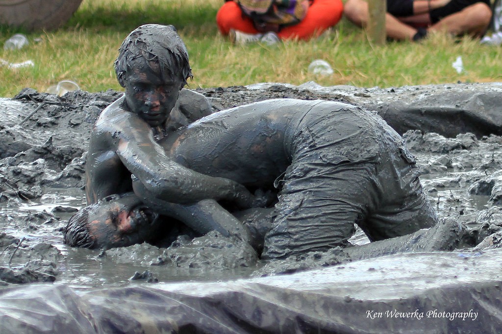 Two mud wrestlers wrestling and soaked in mud.