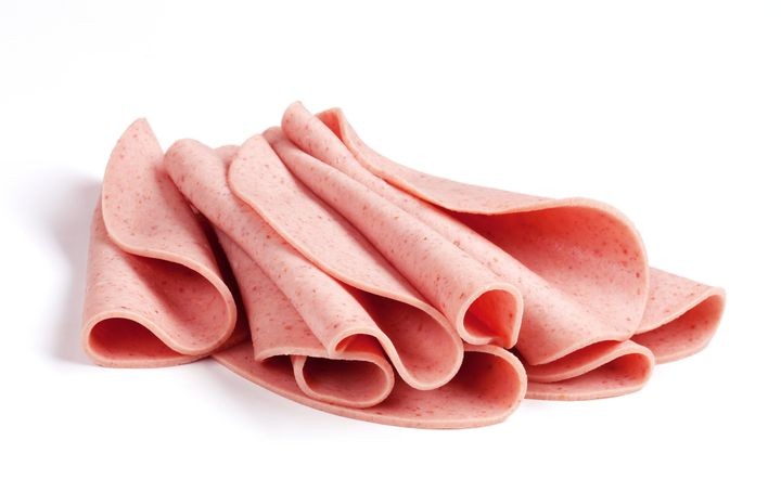 Several baloney slices curled in half, laying next to each other on a white background.