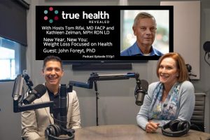 Tom Rifai and Kathleen Zelman at their microphones in studio; headshot of Dr. John Foreyt on the screen in back of them with True Health Revealed logo and title of show.