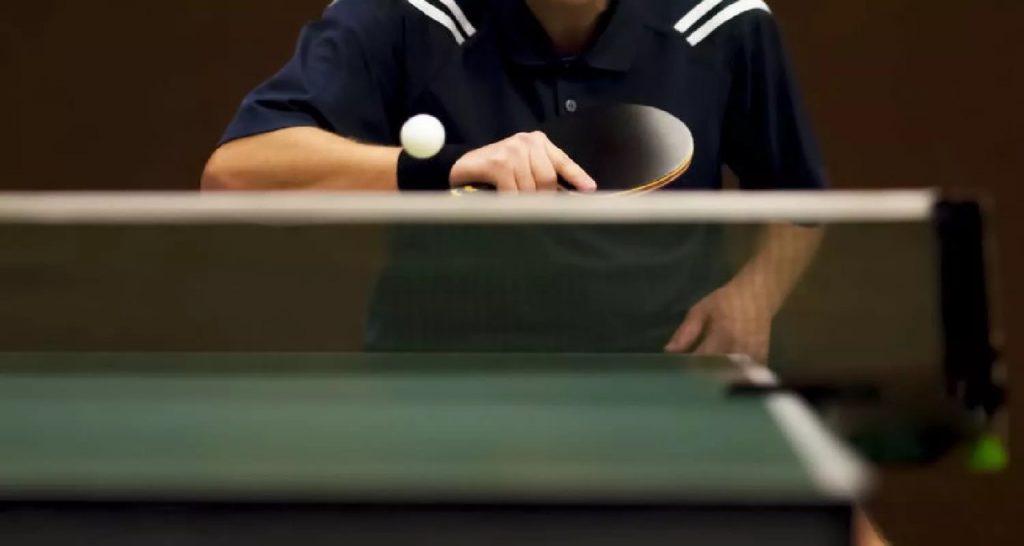 Closeup of a ping pong table with someone about to paddle the ball