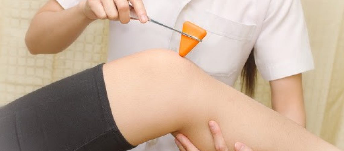 Closeup of a doctor testing a patients knee reflexes. No faces shown in the image.