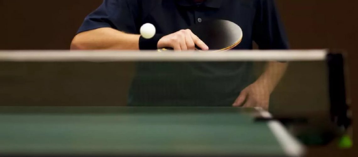 Closeup of a ping pong table with someone about to paddle the ball